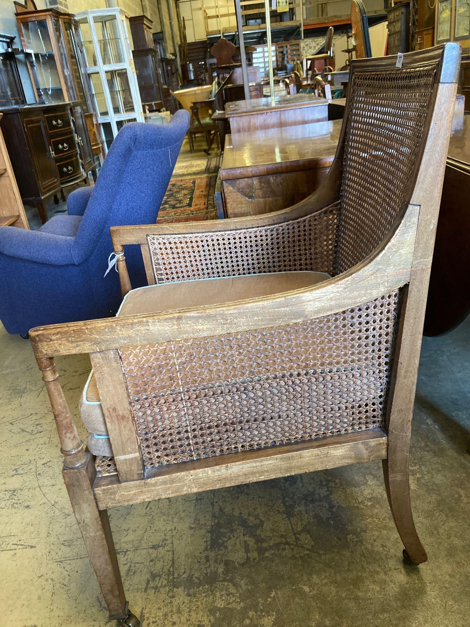 An Edwardian Regency style beech bergere armchair, with caned back and sides, width 60cm